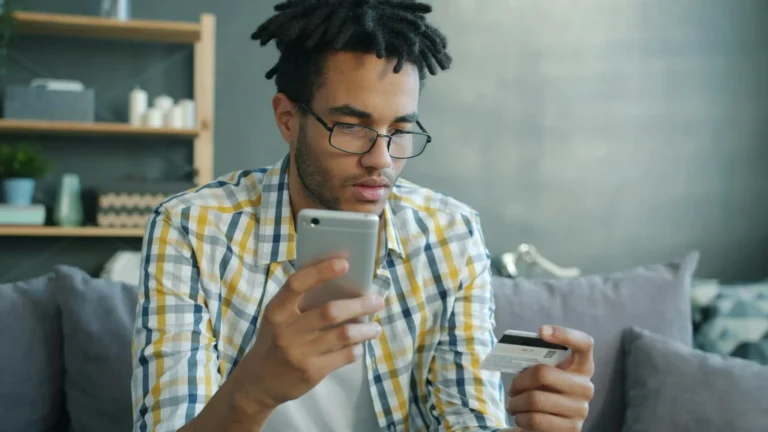 Homem usando cartão e smartphone para pagamento online